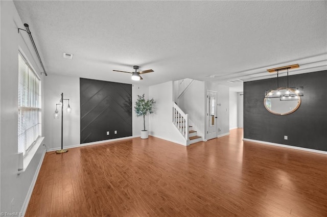 1948 Ray Alexander Dr, Greensboro, NC 27410 - unfurnished living room featuring a textured ceiling, wood finished floors, baseboards, stairway, and ceiling fan