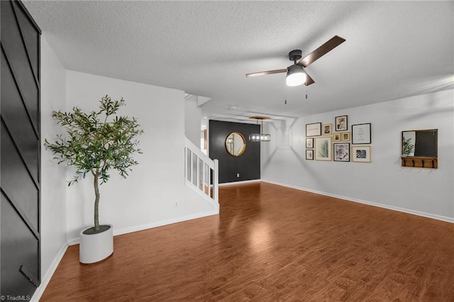 1948 Ray Alexander Dr, Greensboro, NC 27410 - unfurnished living room featuring wood finished floors, stairs, a textured ceiling, a ceiling fan, and baseboards