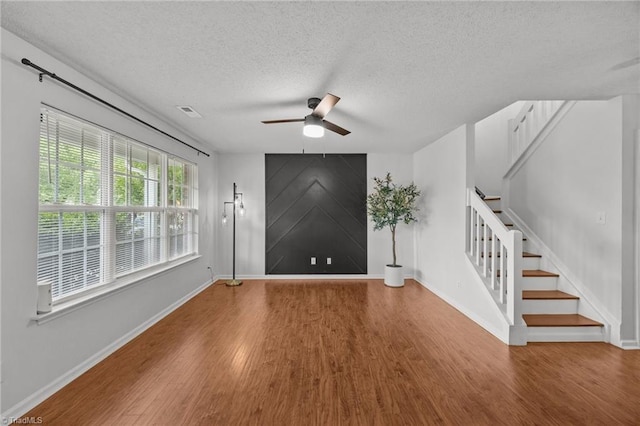1948 Ray Alexander Dr, Greensboro, NC 27410 - unfurnished living room featuring wood finished floors, ceiling fan, stairway, a textured ceiling, and baseboards