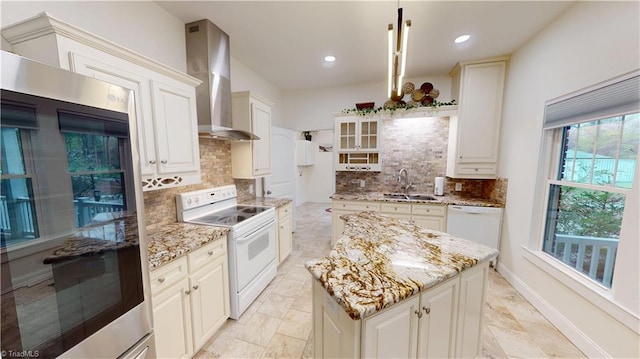 kitchen with a sink, wall chimney exhaust hood, light stone counters, and white appliances