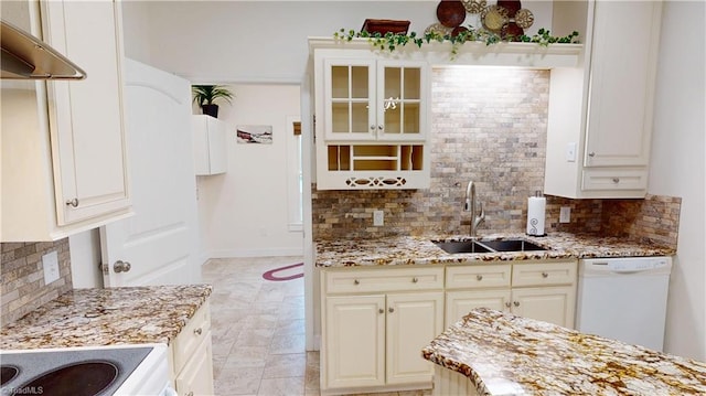 kitchen with a sink, white dishwasher, light stone countertops, and glass insert cabinets