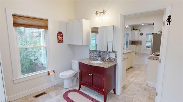 bathroom with baseboards, visible vents, toilet, and vanity