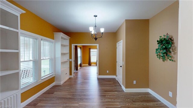 interior space featuring baseboards, wood finished floors, and a notable chandelier
