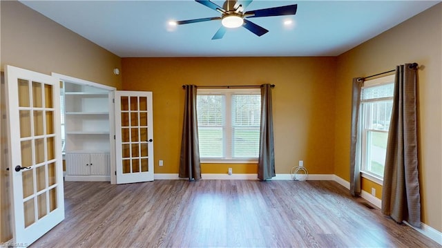 spare room featuring french doors, a ceiling fan, baseboards, and wood finished floors