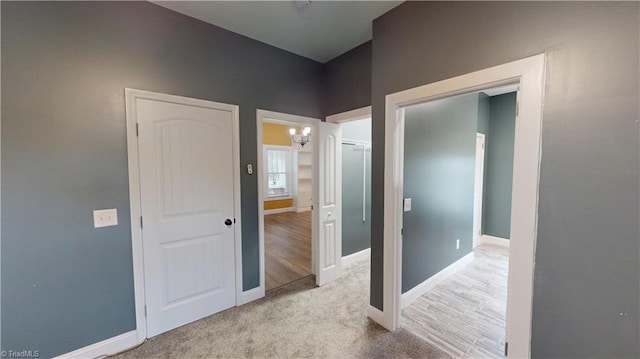 hall with baseboards, a chandelier, and carpet