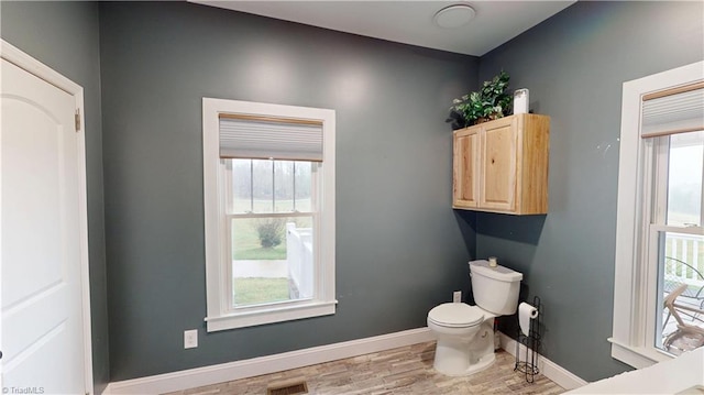 bathroom with baseboards, visible vents, wood finished floors, and toilet
