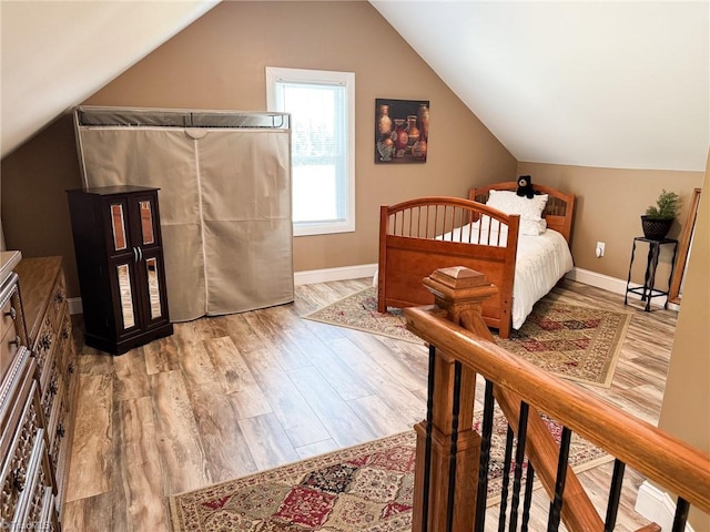 bedroom with baseboards, lofted ceiling, and wood finished floors