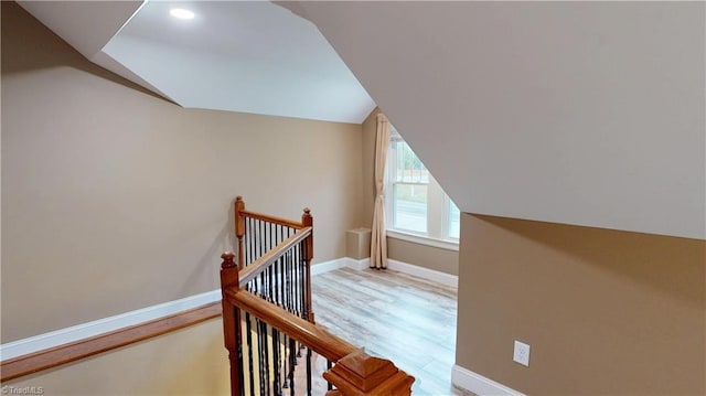additional living space with baseboards, vaulted ceiling, and light wood-type flooring