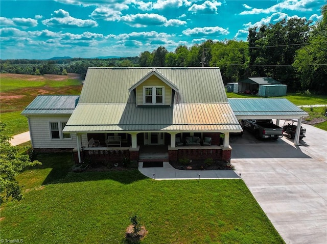 view of front facade with driveway, metal roof, a front lawn, and a porch