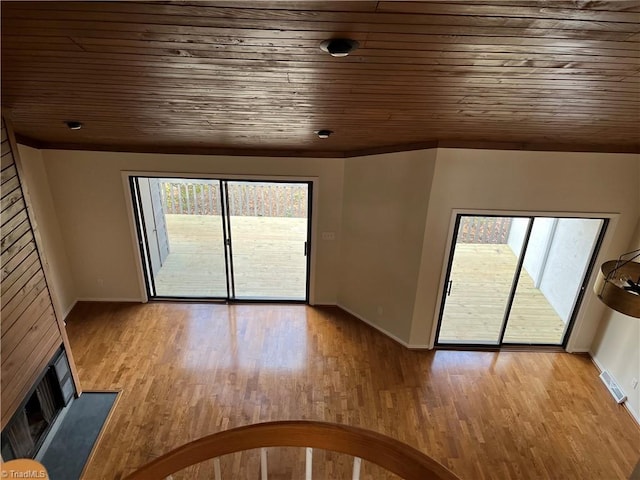 unfurnished living room featuring light wood-type flooring, wood ceiling, and visible vents