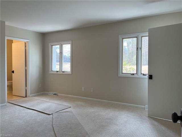 spare room with light carpet, visible vents, and baseboards