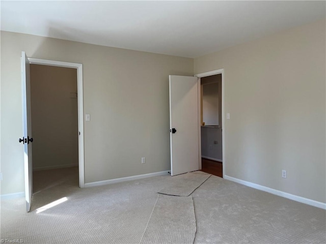 unfurnished bedroom with carpet flooring, a spacious closet, and baseboards