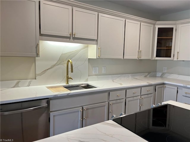 kitchen with tasteful backsplash, dishwasher, glass insert cabinets, light stone counters, and a sink