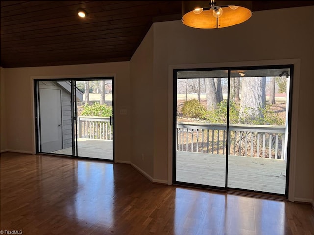 spare room featuring lofted ceiling, baseboards, and wood finished floors