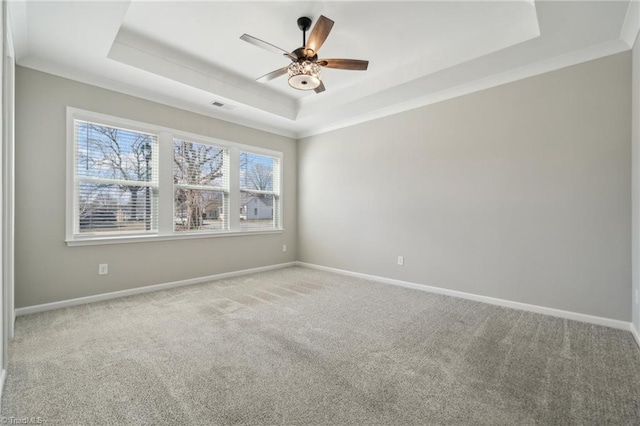 unfurnished room featuring carpet floors, visible vents, baseboards, a tray ceiling, and crown molding