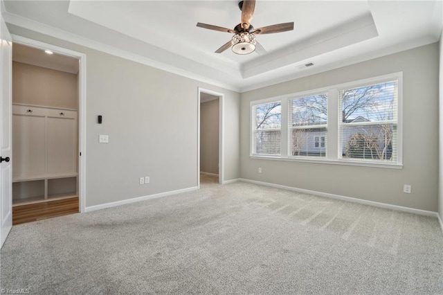 unfurnished bedroom with a walk in closet, a raised ceiling, visible vents, and baseboards