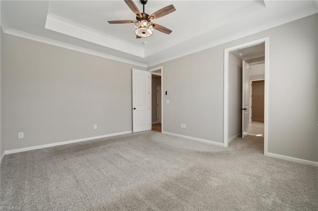 unfurnished room with ceiling fan, carpet floors, baseboards, a tray ceiling, and crown molding