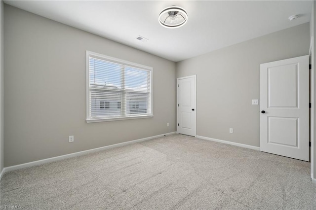 spare room with carpet flooring, visible vents, and baseboards