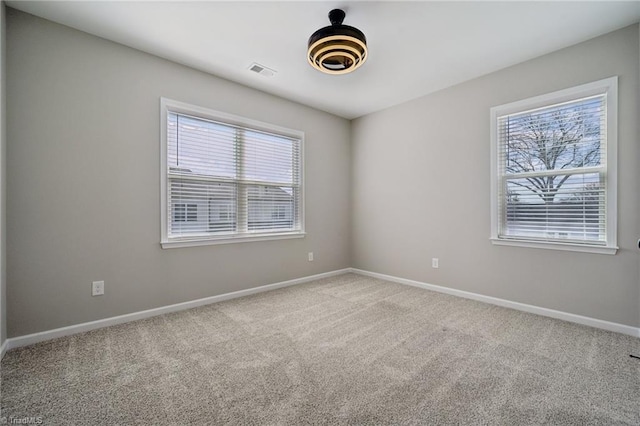 unfurnished room featuring carpet, a healthy amount of sunlight, visible vents, and baseboards