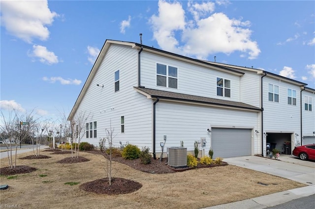 view of home's exterior with concrete driveway, central AC, and an attached garage