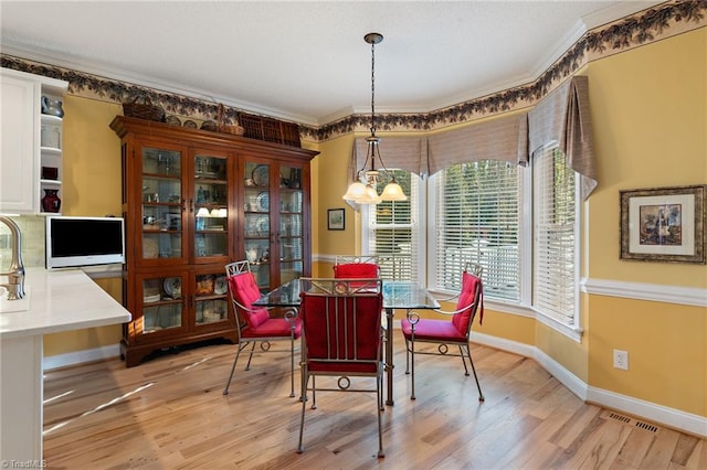 dining space with an inviting chandelier, light wood-type flooring, baseboards, and ornamental molding