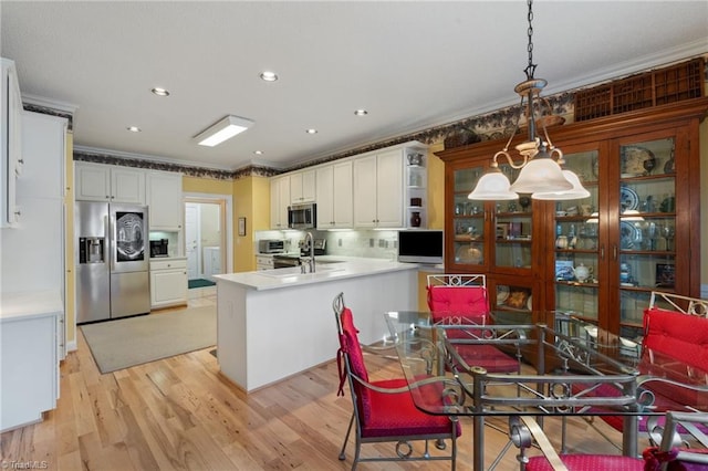 kitchen featuring ornamental molding, a peninsula, stainless steel appliances, and a sink