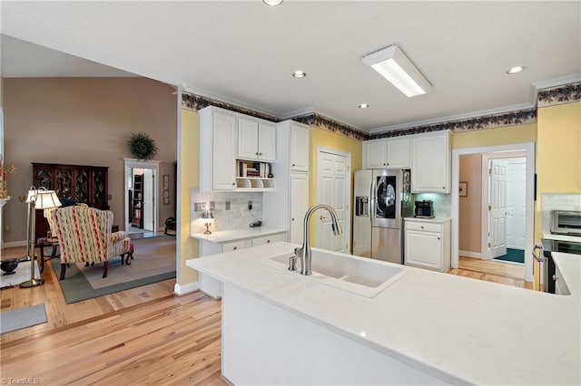 kitchen featuring tasteful backsplash, stainless steel fridge with ice dispenser, light wood-style flooring, white cabinetry, and a sink