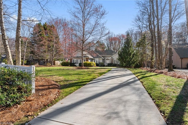 exterior space featuring concrete driveway and a front yard