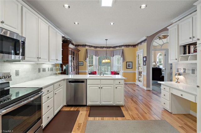 kitchen featuring white cabinetry, a peninsula, stainless steel appliances, and a sink