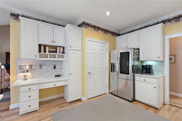 kitchen with stainless steel fridge, light wood-style floors, white cabinets, and built in study area