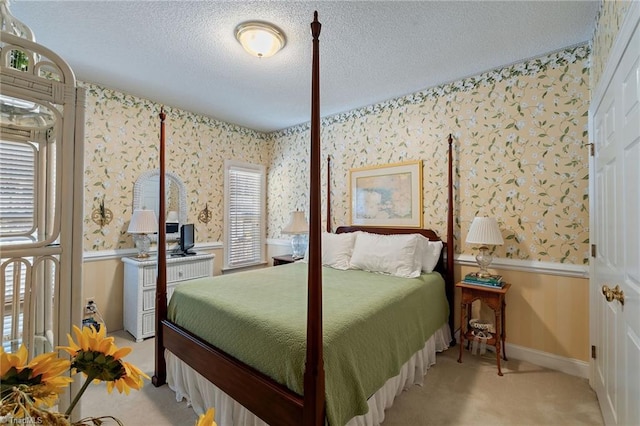 carpeted bedroom with a wainscoted wall, baseboards, a textured ceiling, and wallpapered walls