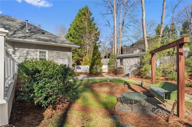 view of yard featuring a storage unit, a patio area, an outdoor structure, and fence