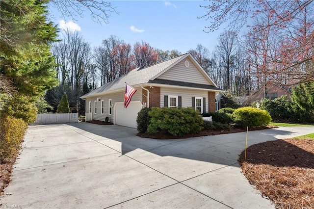 view of side of property featuring an attached garage, fence, brick siding, and driveway