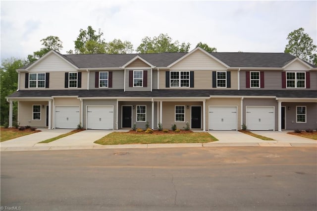 view of property with an attached garage, concrete driveway, and a porch