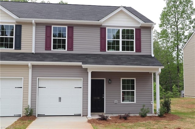 view of front of home featuring a garage, covered porch, driveway, and roof with shingles