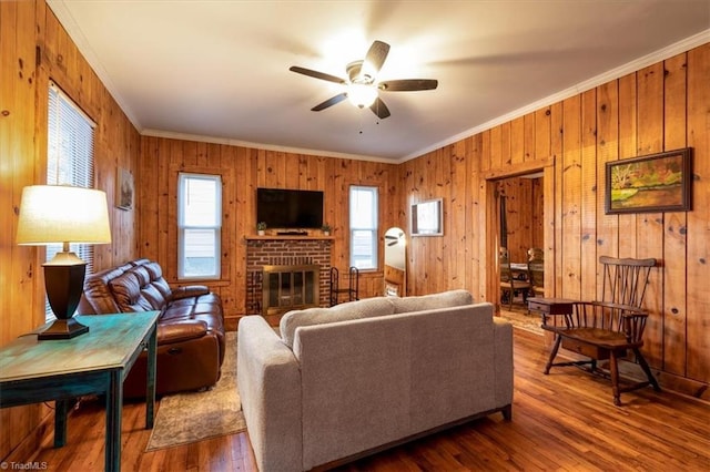 living room with a brick fireplace, crown molding, hardwood / wood-style floors, and ceiling fan