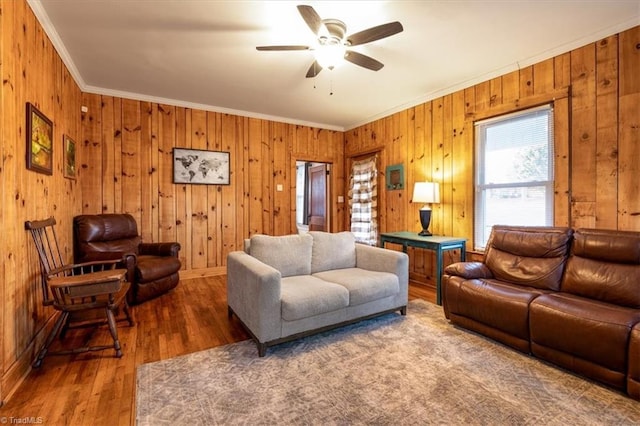 living room with crown molding, wooden walls, dark hardwood / wood-style floors, and ceiling fan