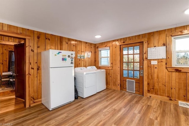 laundry room featuring hardwood / wood-style floors, washer and clothes dryer, ornamental molding, and wood walls