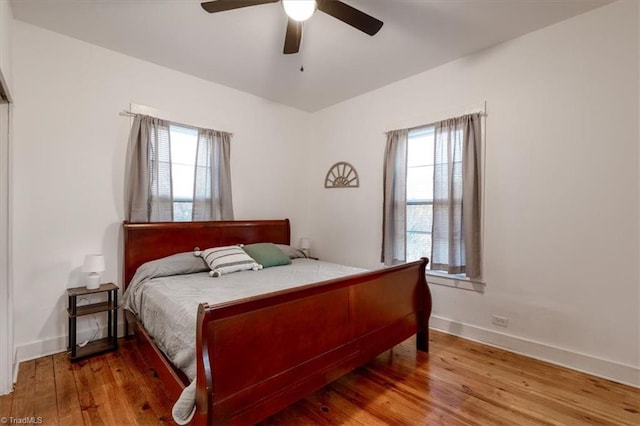 bedroom with multiple windows, hardwood / wood-style flooring, and ceiling fan