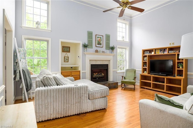 5711 Beaver Pond Trl, Pfafftown, NC 27040 - living room with a high ceiling, ceiling fan, crown molding, a tile fireplace, and wood finished floors