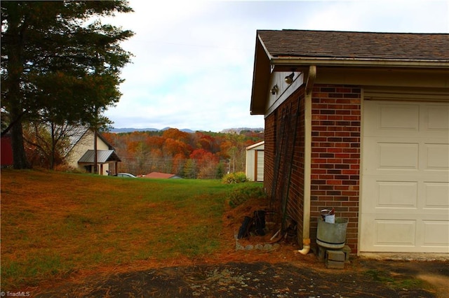 exterior space with a garage, a lawn, brick siding, and a shingled roof