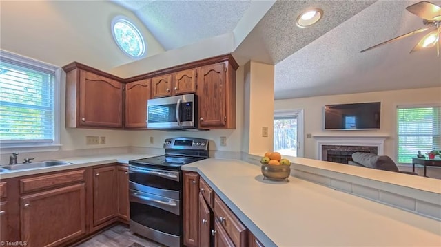 4401 Barndale Ct, Jamestown, NC 27282 - kitchen featuring appliances with stainless steel finishes, light countertops, a textured ceiling, a fireplace, and ceiling fan