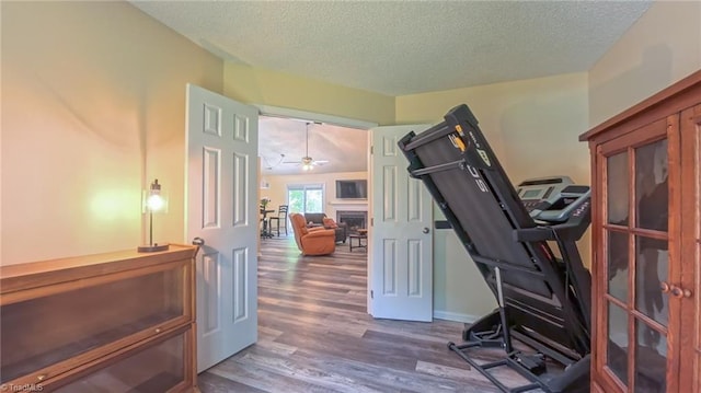 4401 Barndale Ct, Jamestown, NC 27282 - exercise room featuring a fireplace, wood finished floors, a textured ceiling, and a ceiling fan