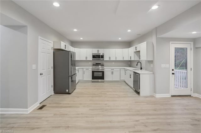 kitchen featuring white cabinets, light wood-type flooring, sink, and appliances with stainless steel finishes