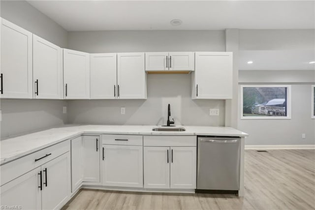 kitchen with stainless steel dishwasher, white cabinets, sink, and light hardwood / wood-style flooring