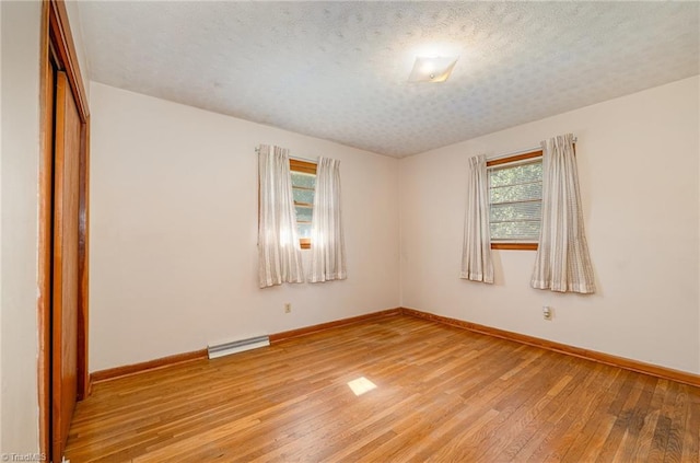 spare room featuring light wood-style floors, baseboards, a wealth of natural light, and visible vents