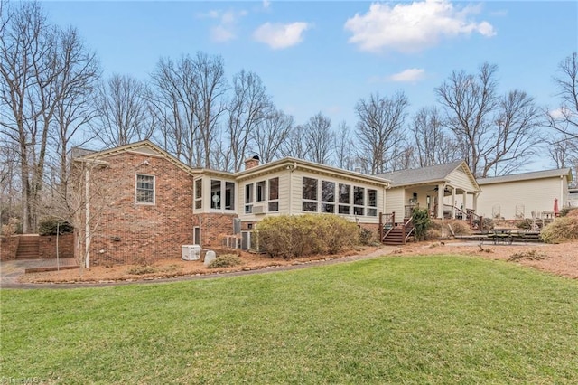 back of house with brick siding, a lawn, and a chimney