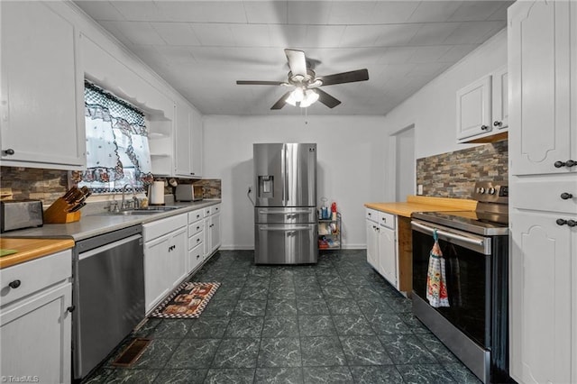 2719 NC Highway 87, Graham, NC 27253 - kitchen with stainless steel appliances, a sink, white cabinetry, a ceiling fan, and tasteful backsplash
