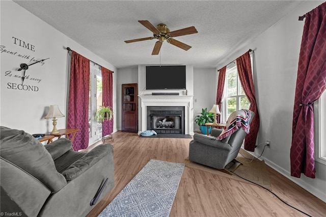 2719 NC Highway 87, Graham, NC 27253 - living room with a ceiling fan, wood finished floors, a textured ceiling, a fireplace with raised hearth, and baseboards