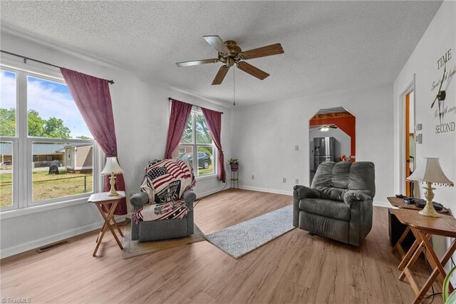 2719 NC Highway 87, Graham, NC 27253 - living room featuring wood finished floors, a ceiling fan, a textured ceiling, arched walkways, and baseboards